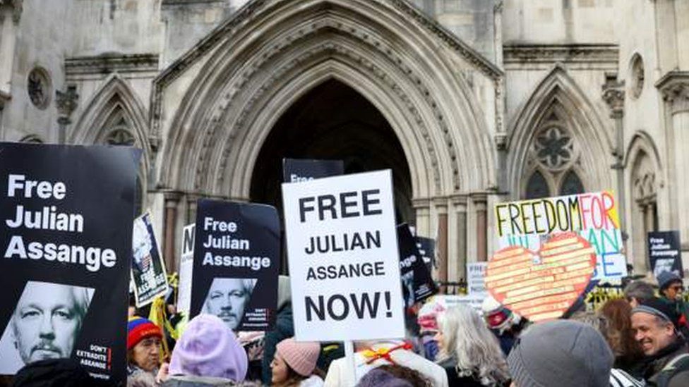 Assange supporters hold placards outside the High Court