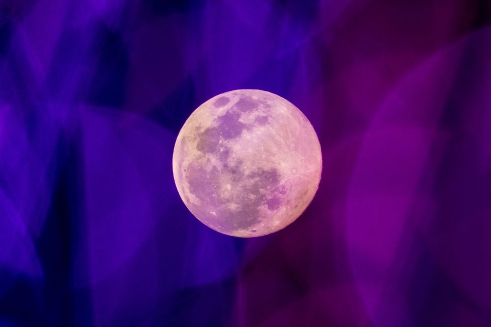 The Wolf Moon is pictured through coloured fairy lights hanging outside a shopping mall in Bangkok on 17 January 2022