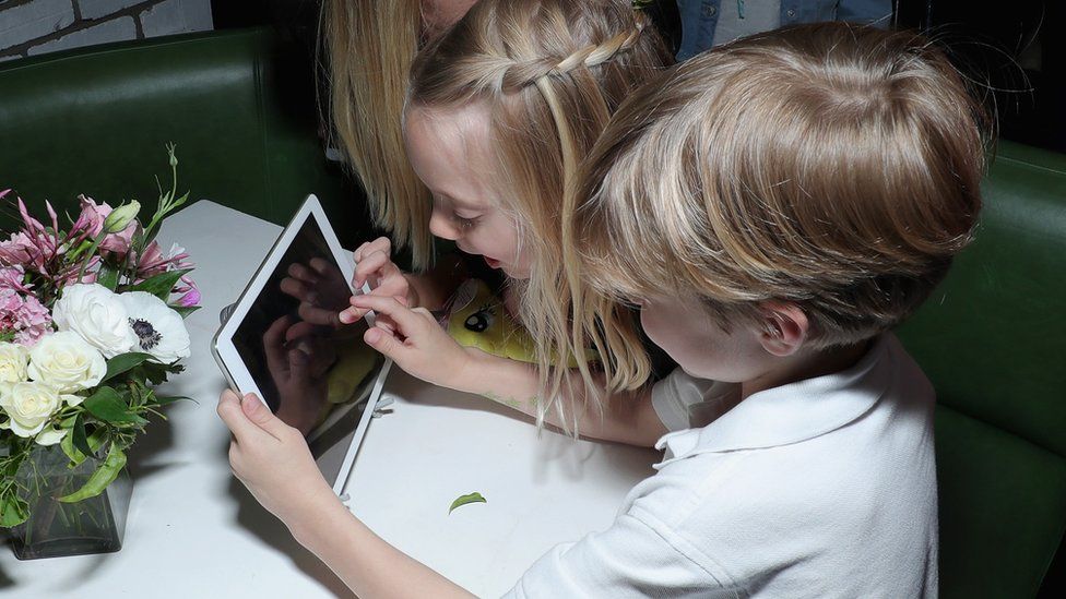 A little boy and girl play with a tablet