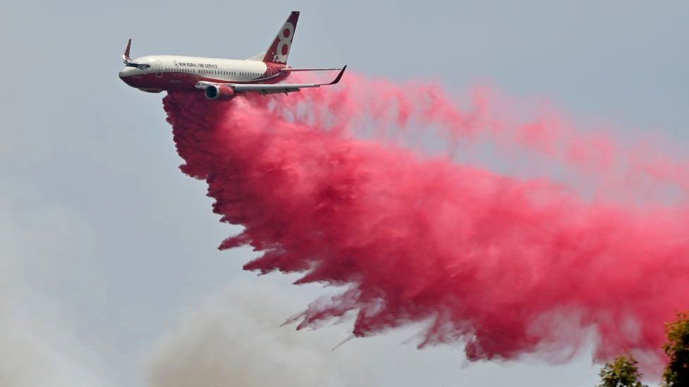 A Rural NSW Fire Service plane drops fire retardent on an out of control bushfire near Taree
