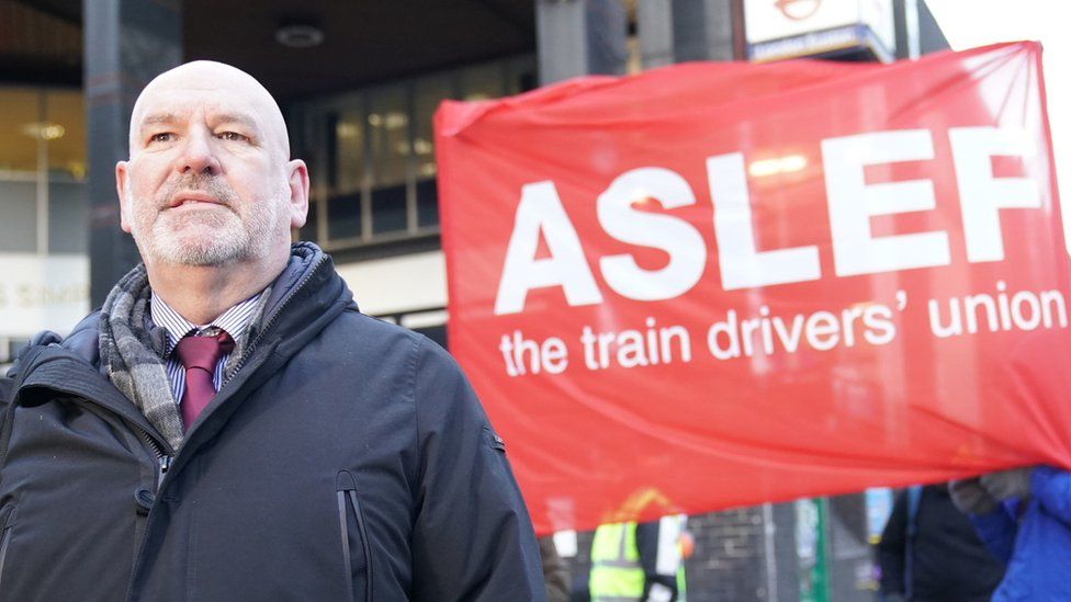 Mick Whelan of Aslef stands in front of a union banner