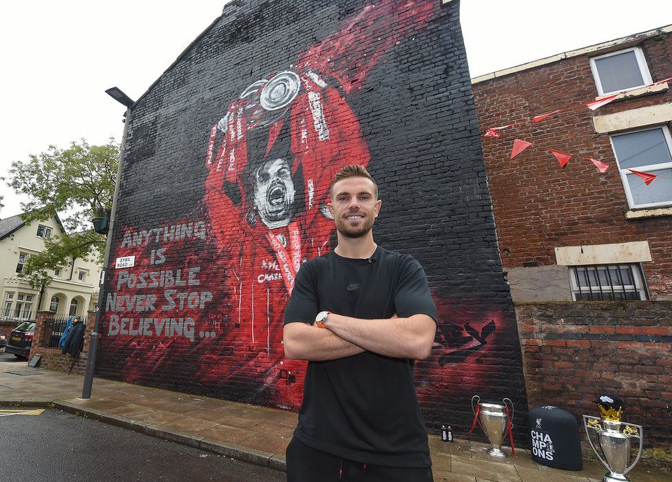 Jordan Henderson standing in front of a mural of himself in Liverpool