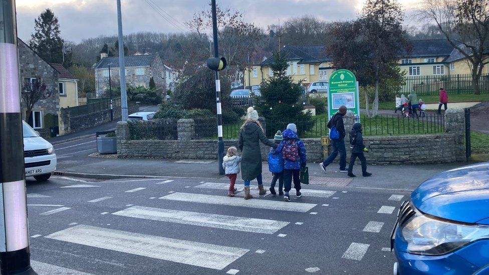 Children and parents cross the zebra crossing outside a school