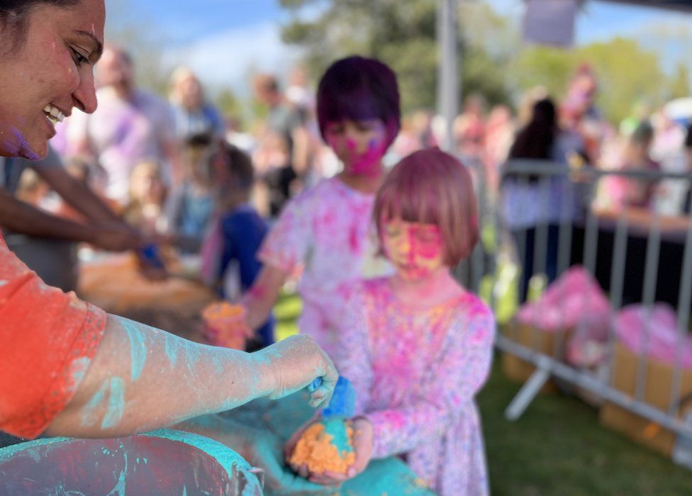 A small girl is handed some coloured paint powder