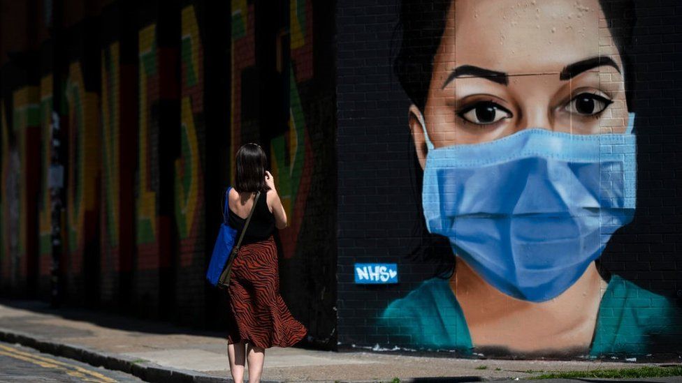 A woman takes a photo of graffiti on Brick Lane in East London on April 23, 2020