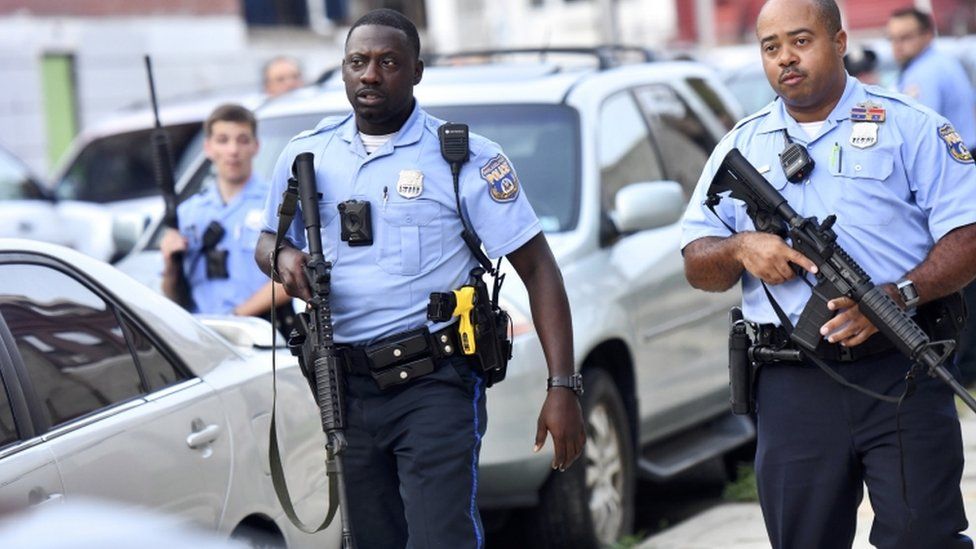 Police officers hold guns near the scene of a shooting in Philadelphia