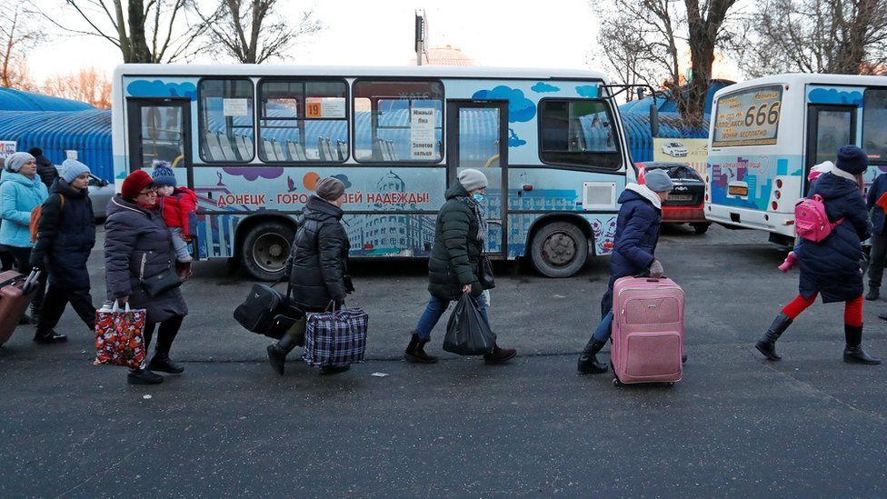 People walk to board a bus during the evacuation of local residents to Russia, in the rebel-controlled city of Donetsk, Ukraine