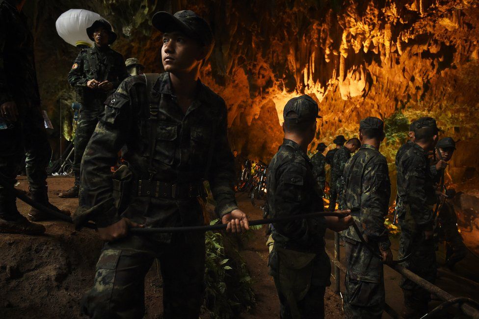 Soldiers hold an electric cable in a cave