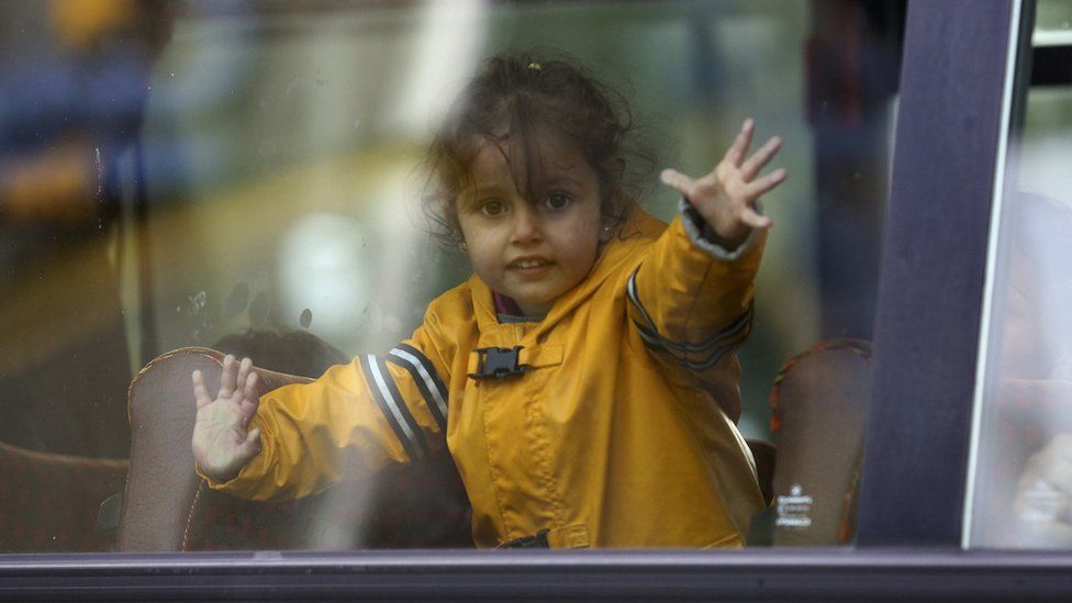Little refugee girl looks out of bus in Germany