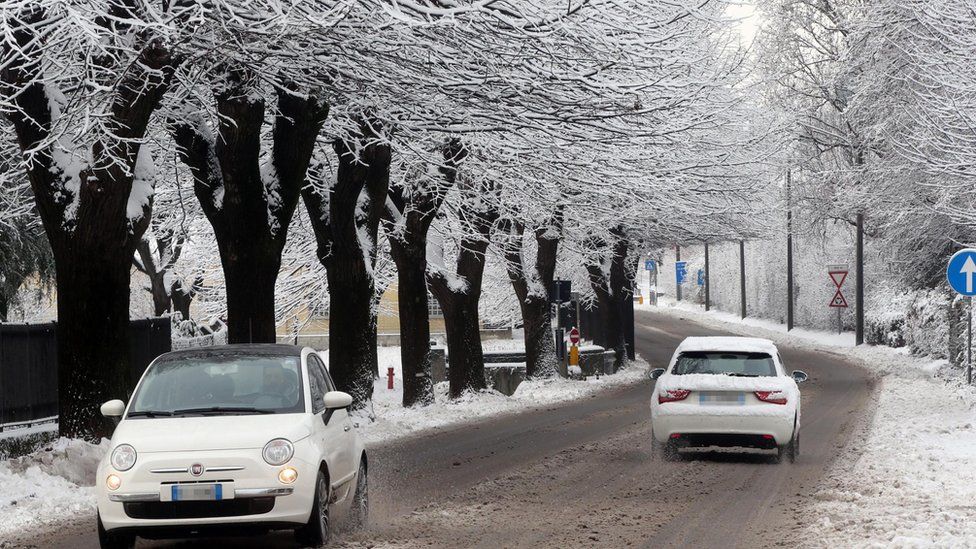 Cars travel through an area covered in ice and snow in freezing temperatures in Como, northern Italy, 13 January