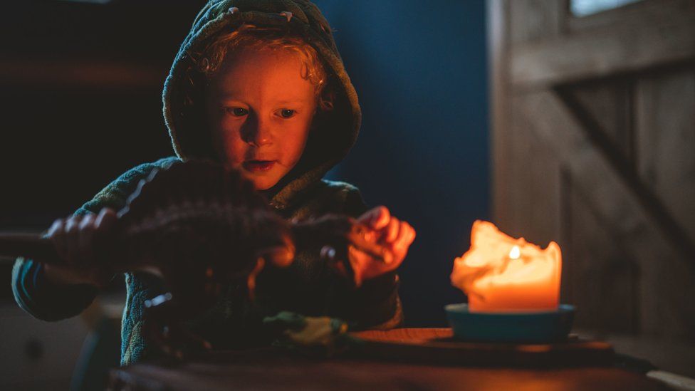 Boy plays with toy by candlelight