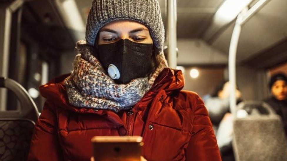 Woman wearing mask looking at mobile phone