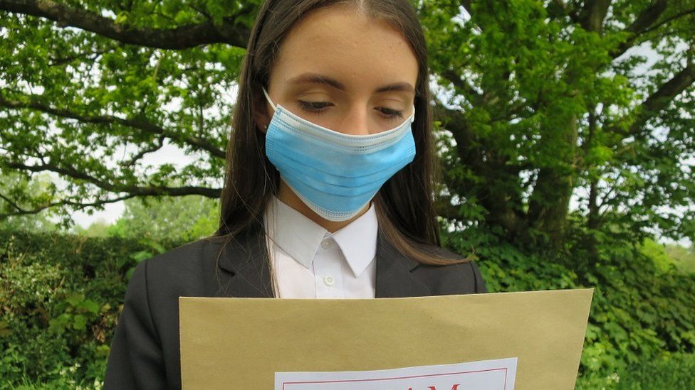 Student receives her exam results after the coronavirus pandemic 2020. Focal point is on the brown envelope. Taken in Leicestershire, UK.