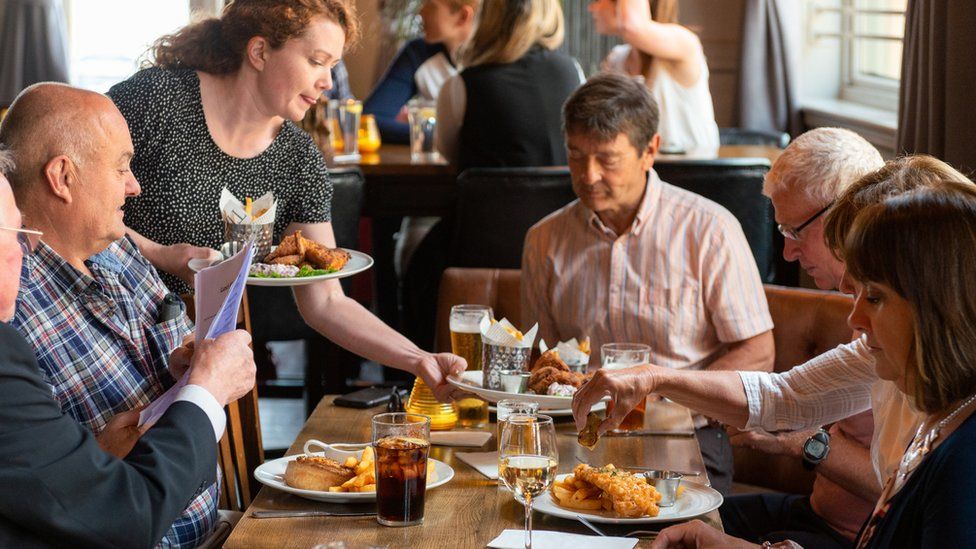 Stock picture of a waitress serving food in a pub
