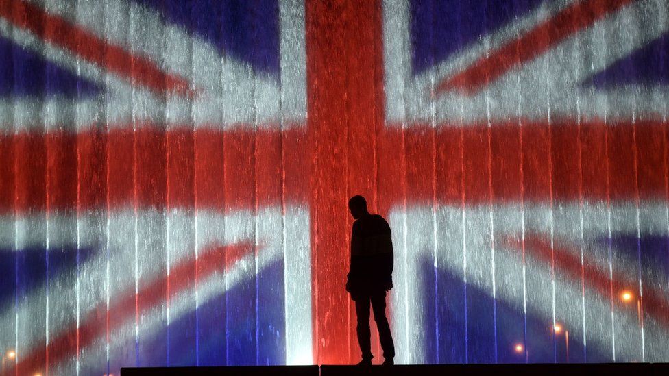 A man stands in front of a fountain illuminated with the colours of the United Kingdom flag on May 23, 2017, in Zagreb,