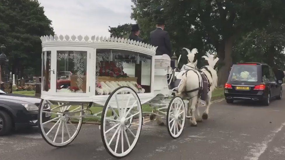 Horse drawn carriage carrying coffin