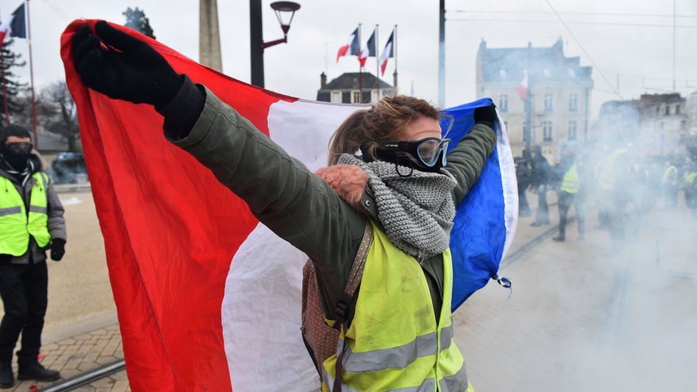 A protester holds a French flag during an anti-government demonstration called by the "Yellow Vest" (Gilets Jaunes) movement on January 12, 2019, in Le Mans, western France