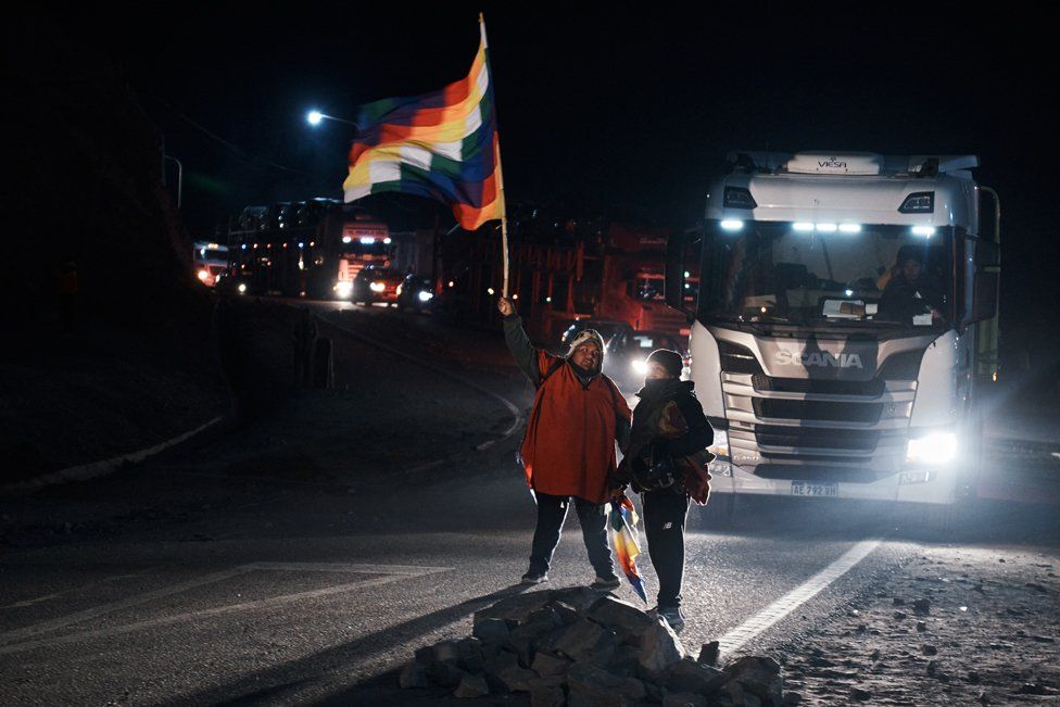 A man waves the flag of the indigenous communities (Wiphala), while giving way to vehicles during the roadblock in Purmamarca, Jujuy province, Argentina, June 22, 2023.