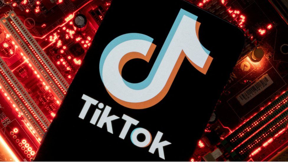 Смартфон с отображаемым логотипом TikTok на материнской плате компьютера.