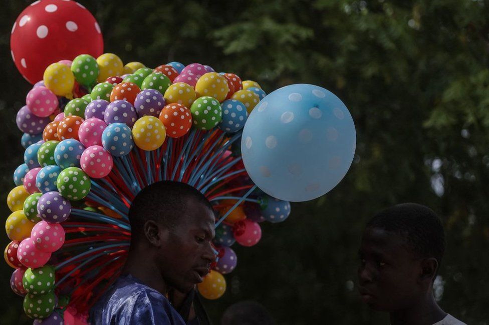 A Nigerian balloon vendor displays his wares at the celebration of the wedding of 1800 couples at Kano Central Mosque, Kano State, Nigeria on October 13, 2023. The mass wedding is sponsored by the Kano State government in Nigeria to help widows and divorcees get remarried.
