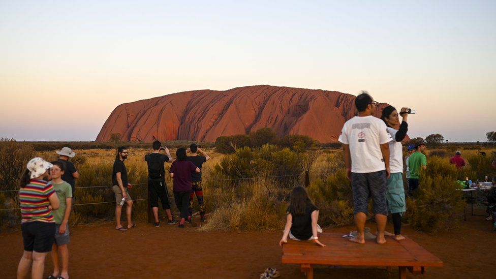 Tourists gather to watch Uluru at sunset