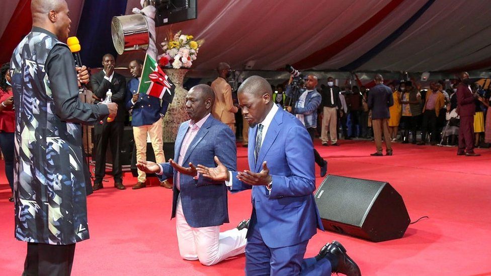 Президент Уильям Руто (слева) становится на колени в церкви