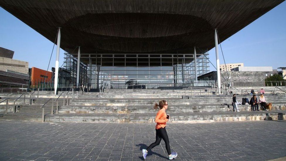 A woman jogging in front of the Senedd