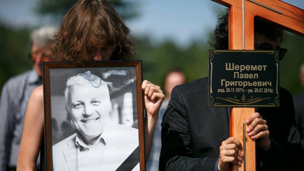 Relatives hold a portrait of killed journalist Pavel Sheremet and a cross during his funeral at a cemetery in Minsk, Belarus, Saturday, 23 July 2016.