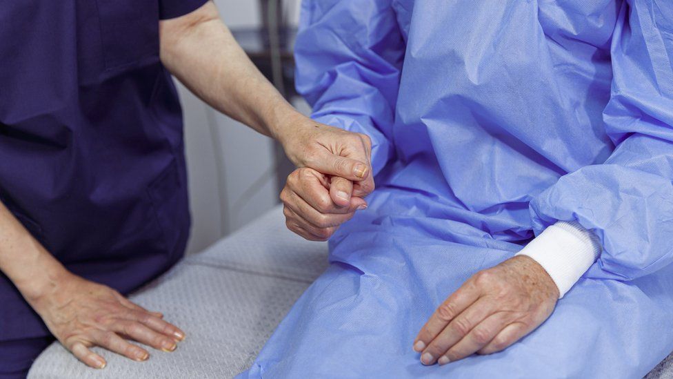 Close up of an unrecognizable hospitalized woman holding hands with and receiving encouragement from her nurse