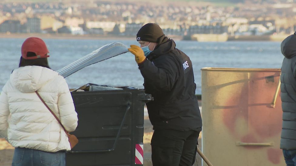 Police officer searching a bin