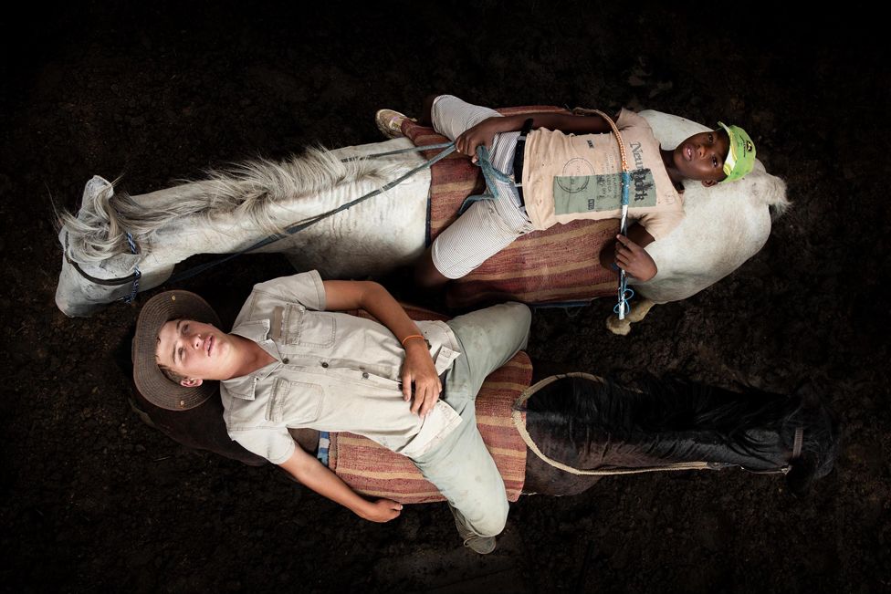 Вид с воздуха на двух молодых людей, лежащих на спинах лошадей