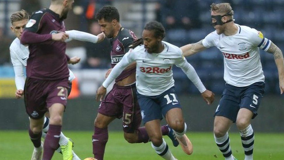 Wayne Routledge of Swansea is tackled by Daniel Johnson of Preston North End and Tom Clarke of Preston North End
