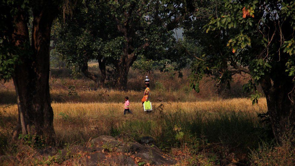 A woman walking to work with her child in Odisha state