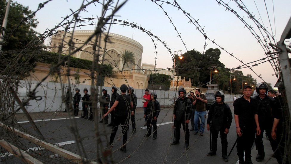 File photo of riot police standing behind a barricade near the Ittihadiya presidential palace in Cairo (26 April 2014)