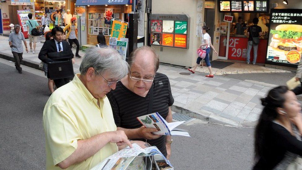Two male foreign tourists consult a map on a street in Tokyo