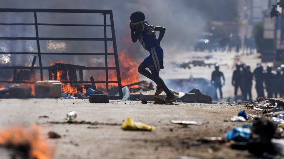 A boy runs past barricades as Senegalese demonstrators clash with riot police during a protest against the postponement of the Feb. 25 presidential election, in Dakar, Senegal