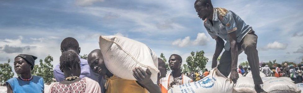 South Sudanese refugees seen collecting cassava flour provided by the World Food Program at the refugee settlement