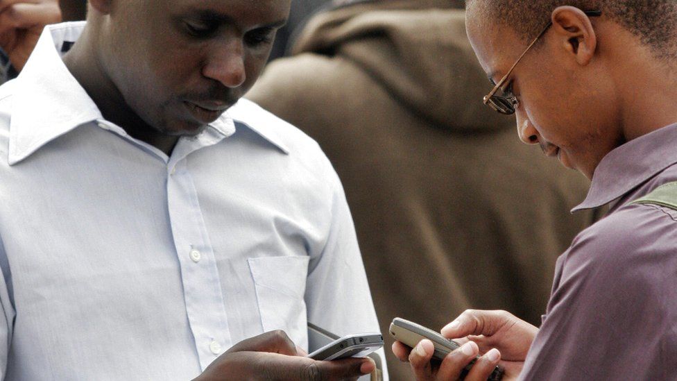 Two Kenyans texting on their phones - archive shot