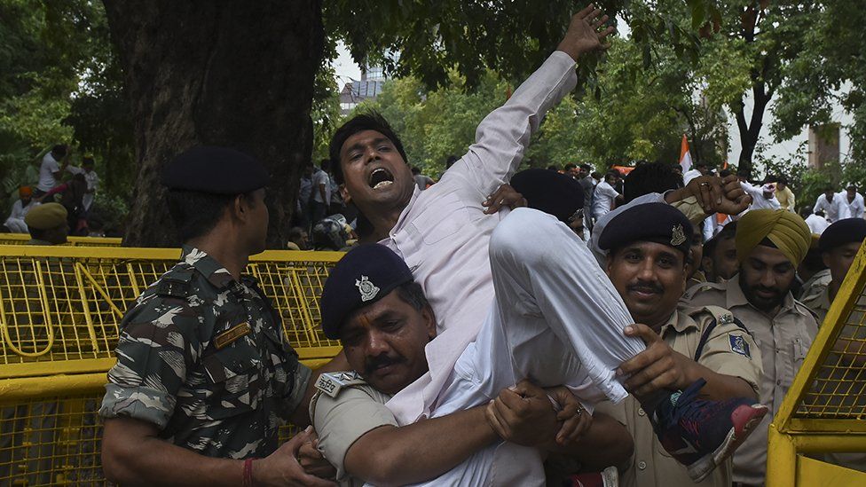 A protestor being held by a police officer
