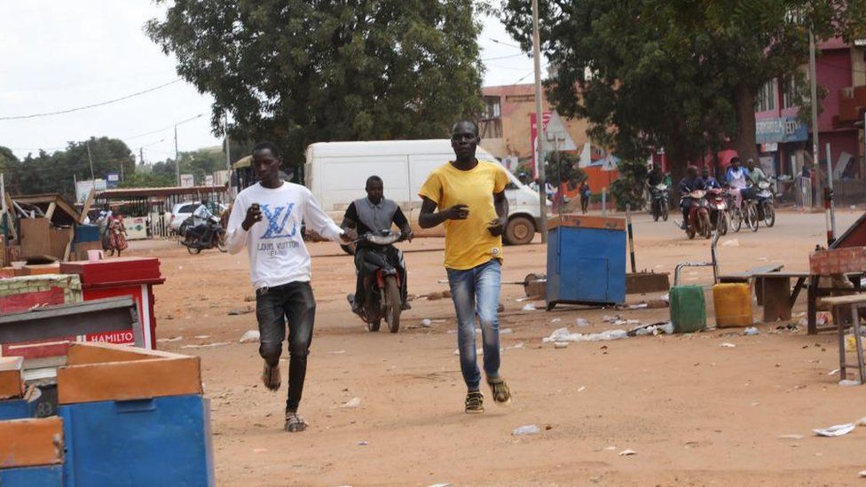 Men run through a deserted marketplace in Burkina Faso's capital city Ouagadougou on Saturday