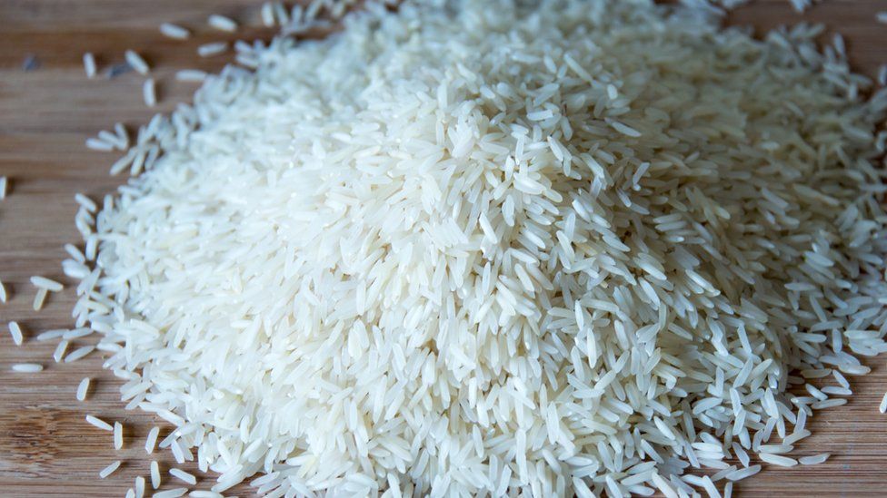 Small pile of long grain white rice over a wooden surface