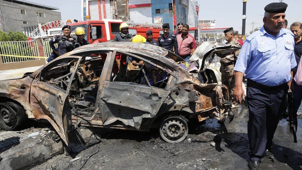 Iraqi security forces inspect the scene of a suicide car bomb attack in Basra