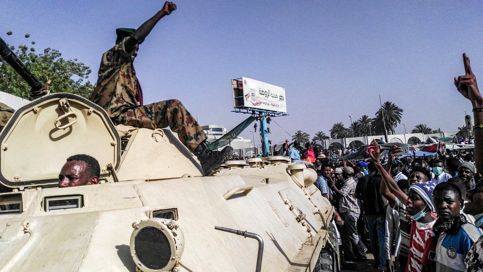 Sudanese protesters salute a military armoured vehicle as they gather during a demonstration in front of the military headquarters in the capital Khartoum, 9 April 2019