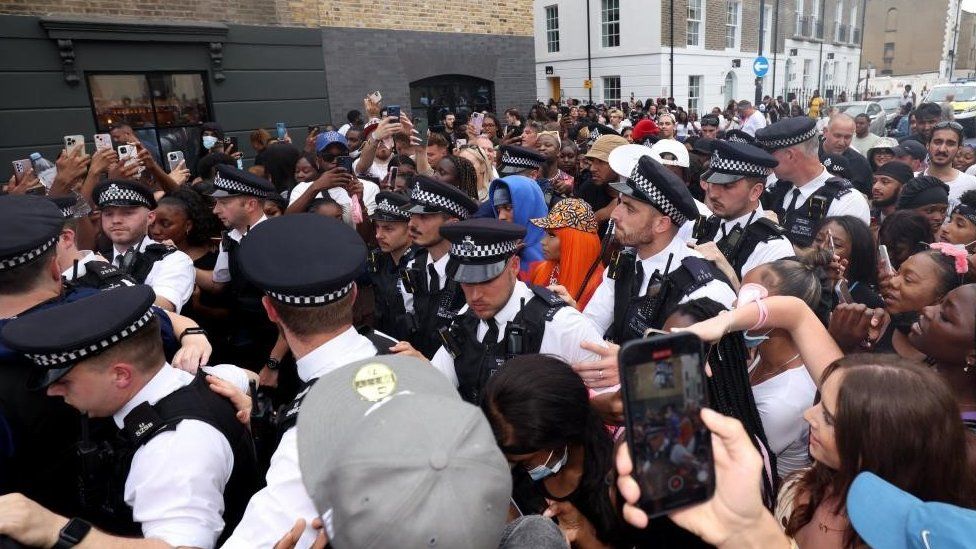 Police officers surround US rapper Nicki Minaj at fans attend a meet and greet at Camden's Cafe Koko