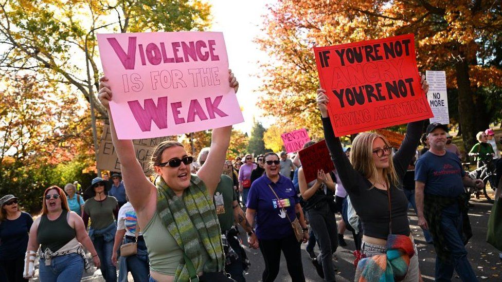 Women hold signs at a rally to call for action to end violence against women, in Canberra, Australia 28 April 2024.