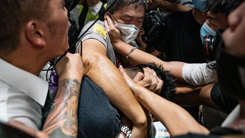 An injured man whom protesters accused of being an undercover police officer is being taken by medical personal after clashes with anti-government protesters