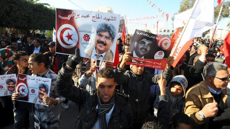Tunisians, carrying portraits of assassinated opposition figure Mohamed Brahmi, gather to mark the third anniversary of the uprising that toppled deposed president Zine El Abidine Ben Ali