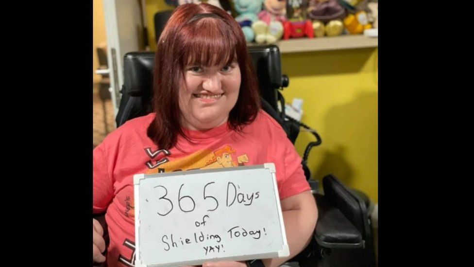 Michaela holding a sign which says '365 days of shielding today, yay' as taken on 12 March