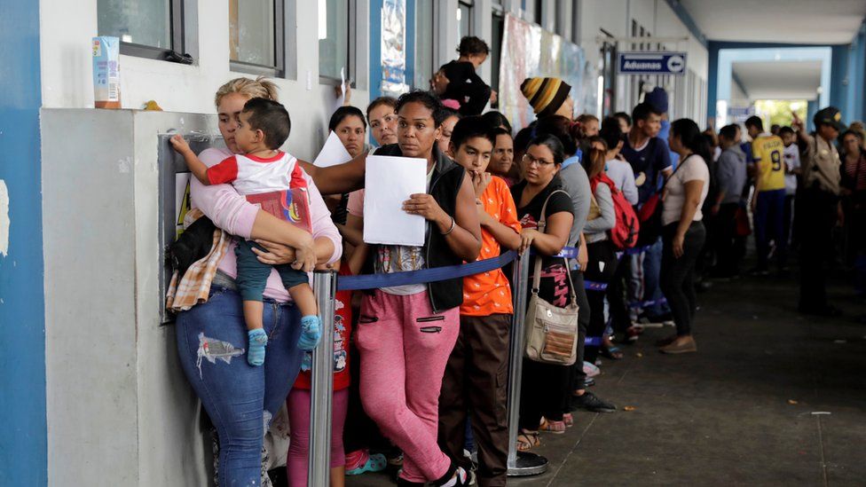 Venezuelans queue outside an immigration office in Tumbes, Peru