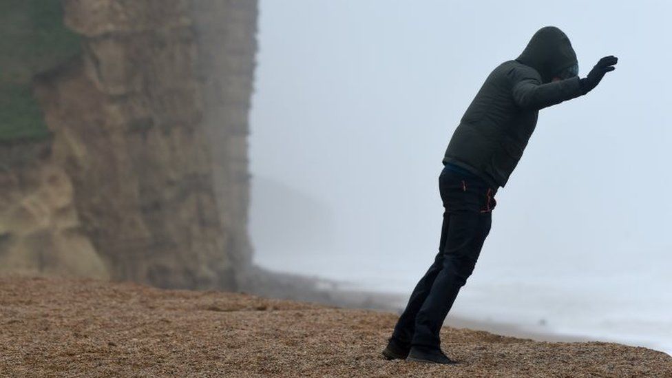 A person leans into the wind in West Bay, Dorset